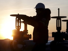 A worker checks the valve of an oil pipe at the Lukoil company owned Imilorskoye oil field outside the West Siberian city of Kogalym, Russia.