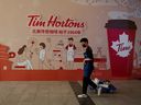 Ein Mann geht an einem Schaufensterplakat vorbei, das für die Eröffnung eines Cafés der kanadischen Kaffee- und Fast-Food-Kette Tim Hortons in Peking, China, am 6. Juli 2020 wirbt. 