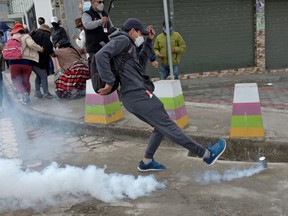 A demonstrator kicks a gas canister at riot police during clashes in Panzaleo, Cotopaxi Province, Ecuador, on October 26, 2021 during a protest against the economic policies of the government, including fuel price hikes, amid a state of emergency. - Indigenous people, workers and students will join forces to stage a protest against Ecuador's President Guillermo Lasso, who on October 18 declared a state of emergency in the country grappling with a surge in drug-related violence, and ordered the mobilization of police and military in the streets.