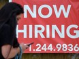 A woman walks by a 'Now Hiring' sign outside a store on Aug. 16, 2021 in Arlington, Virginia.