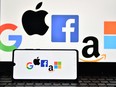 (FILES) In this file photo taken on December 18, 2020, an illustration picture taken in London shows the logos of Google, Apple, Facebook, Amazon and Microsoft displayed on a mobile phone and a laptop screen. - US lawmakers take a first step toward regulating Big Tech on June 23, 2021 with a vote on a series of bills with potentially massive implications for large online platforms and consumers who use them. (Photo by JUSTIN TALLIS / AFP) (Photo by JUSTIN TALLIS/AFP via Getty Images)