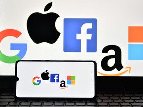 (FILES) In this file photo taken on December 18, 2020, an illustration picture taken in London shows the logos of Google, Apple, Facebook, Amazon and Microsoft displayed on a mobile phone and a laptop screen. - US lawmakers take a first step toward regulating Big Tech on June 23, 2021 with a vote on a series of bills with potentially massive implications for large online platforms and consumers who use them. (Photo by JUSTIN TALLIS / AFP) (Photo by JUSTIN TALLIS/AFP via Getty Images)