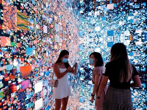 Visitors in front of an immersive art installation titled 'Machine Hallucinations — Space: Metaverse' by media artist Refik Anadol at the Digital Art Fair in Hong Kong, China on Sept. 30, 2021. REUTERS/Tyrone Siu