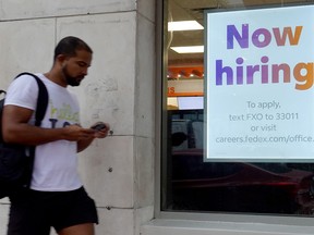 A 'Now hiring" sign hangs near the entrance to a Fedex store on Nov. 5, 2021 in Miami Beach, Florida.