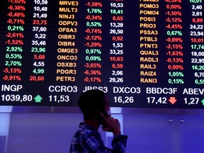 A man stands near an electronic board showing the recent fluctuations of market indices on the floor of Brazil's B3 Stock Exchange in Sao Paulo, Brazil on Oct. 28, 2021.