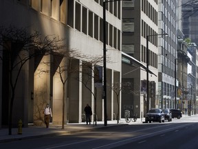 Pedestrians walk on the sidewalk in the financial district of Toronto on May 22, 2020.