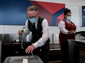 Delta Airline employees check in luggage at the Ronald Regan National Airport on July 22, 2020 in Arlington, Virginia.