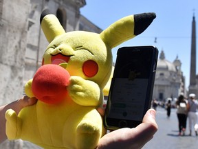 A gamer holds a Pokémon mascot and his mobile phone as he plays with the Pokémon Go application. The game was so popular in its soft launch in 2016 it was released earlier, putting a huge strain on the company's servers.