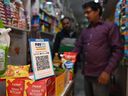 Ein Mann kauft in einem Lebensmittelgeschäft ein, in dem auf einem Markt in Neu-Delhi ein Barcode für Paytm, eine indische Handy-basierte digitale Zahlungsplattform, ausgestellt ist.