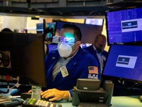 A trader wears "2022" glasses while working on the floor of the New York Stock Exchange (NYSE) in New York, U.S., on Friday, Dec. 31, 2021. U.S. stocks swung between gains and losses, with moves exacerbated by thin trading on the last session of the year.