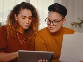 Shot of a young lesbian couple doing paperwork while using a digital tablet at home