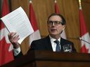 Governor of the Bank of Canada Tiff Macklem holds up a document as he speaks during a joint news conference in Ottawa, on Dec. 13, 2021. 