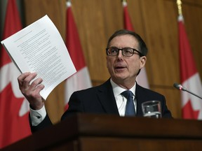 Governor of the Bank of Canada Tiff Macklem holds up a document as he speaks during a joint news conference in Ottawa, on Dec. 13, 2021.