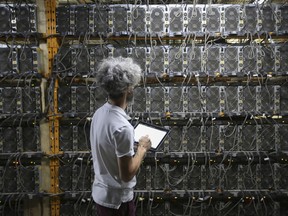 A worker inspects Bitcoin mining machines at a Canada Computational Unlimited Inc. computation center in Joliette, Quebec.