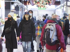 People wear face masks as they walk through a market in Montreal on Nov. 28, 2021, as the COVID-19 pandemic continues in Canada and around the world.