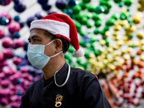 A man wearing a face mask and a Christmas Santa hat walks below decorations outside a shopping mall in Bangkok on December 6, 2021 as Thailand recorded on Monday its first case of the Covid-19 coronavirus Omicron variant.