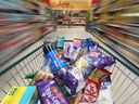 Ein Einkaufswagen voller Lebensmittel wird in einem Supermarkt von Morrisons in Crawley, Großbritannien, durch einen Gang geschoben
