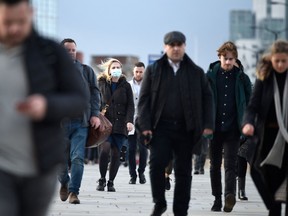 Commuters walk over London Bridge during the morning rush hour in central London. Britain's acute cost-of-living crunch will hit in April.