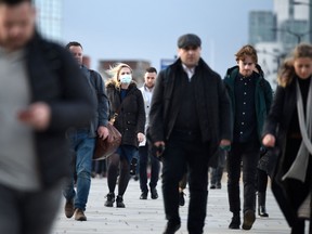 Commuters walk over London Bridge during the morning rush hour in central London. Britain's acute cost-of-living crunch will hit in April.