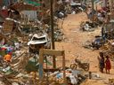 Bewohner gehen an Trümmern von Häusern und anderen Gebäuden vorbei, die zerstört wurden, als am Freitag ein Fahrzeug mit Bergbausprengstoff entlang einer Straße in Apiate, Ghana, explodierte.