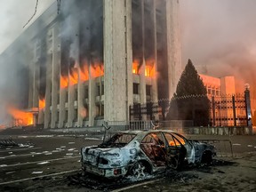 A burnt car is seen by a government office on fire in Almaty, the capital of Kazakhstan. Protests are spreading across the Central Asian state over the rising fuel prices.