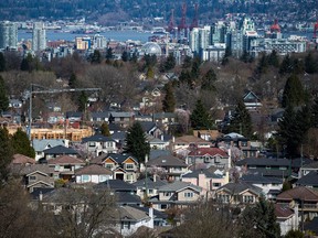 A condo building is seen under construction surrounded by houses as condo towers are seen in the distance in Vancouver, B.C., on Friday March 30, 2018. The local real estate board says the benchmark price of a detached home in Metro Vancouver fell nearly 10 per cent year over year as more sellers listed properties but house hunters continued to take their time.