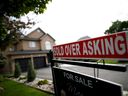 A real estate sign that reads 'For Sale' and 'Sold Above Asking' stands in front of housing in Vaughan.