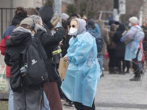 A health-care worker talks to people as the wait to receive a COVID-19 test in Montreal on Dec. 17, 2021, as the COVID-19 pandemic continues in Canada and around the world.