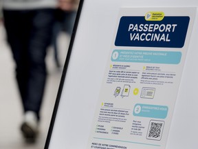 People walk by a sign at a restaurant advising customers of Quebec’s COVID-19 vaccine passport in Montreal on Sept. 6, 2021.