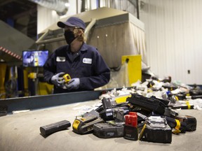 A worker wearing a protective mask sorts batteries at the Li-Cycle lithium-ion battery recycling facility in Kingston.