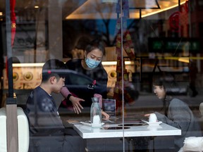 A server attends to customers at a restaurant in the Chinatown district of downtown Toronto.