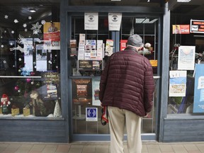 A pedestrian checks the hours of a magazine store in Montreal which was closed on Sunday because of restrictions aimed at curbing coronavirus hospitalizations.