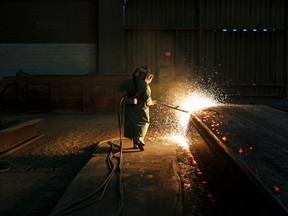 Sparks fly as an employee performs a quality check on a steel slab at the Stelco Holdings Inc. plant in Ontario. Stelco is seeing staff shortages fuelled by the Omicron wave.