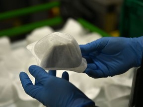 A worker holds up a face mask at a Honeywell facility in Phoenix, Arizona. Honeywell said it would stick to its vaccination policy.