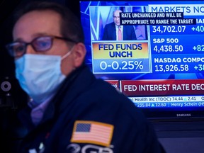 A screen displays the Fed rate announcement as a specialist trader works at his post on the floor of the New York Stock Exchange, Wednesday.