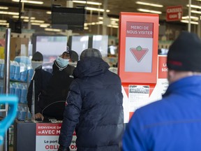 Shoppers wait in line to show their vaccine passports inside a Canadian Tire store in Montreal.