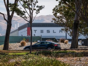 A Tesla Inc. vehicle drives past the company's assembly plant in Fremont, California.