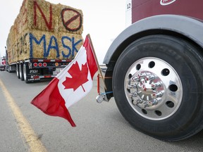 The Canadian flag is reflected in a wheel hub as a truck convoy blocks the highway of the busy U.S. border crossing in Coutts, Alta.