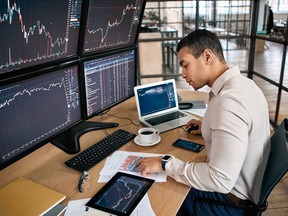 Stock Traiding. Trader sitting at office in front of monitors with data browsing laptop checking documents analyzing stocks price changes concentrated