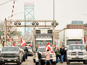 Unterstützer des Truckers Convoy gegen das COVID-19-Impfstoffmandat blockieren am Dienstag den Verkehr auf den nach Kanada führenden Fahrspuren des Grenzübergangs Ambassador Bridge in Windsor, Ontario.  Waren im Wert von etwa 323 Millionen US-Dollar überqueren jeden Tag die Grenze zwischen Windsor und Detroit an der Ambassador Bridge, was sie zum verkehrsreichsten internationalen Grenzübergang Nordamerikas macht.