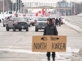 Anti vaccine mandate protestors block the roadway leaving the Ambassador Bridge border crossing, in Windsor, Ontario on Tuesday.