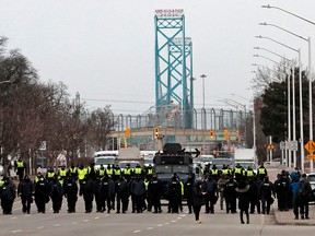 Police gather to clear protestors against COVID-19 vaccine mandates who blocked the entrance to the Ambassador Bridge in Windsor, Ontario, on Sunday.