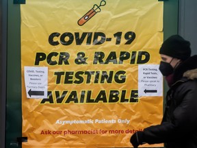 A pedestrian walks past a sign advertising COVID-19 testing on Toronto’s Queen Street in January. Employee absences hit a record high last month.