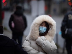 A person bundled up in a heavy jacket for the cold weather wears a face mask to curb the spread of COVID-19 in Vancouver.