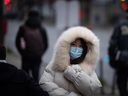 Eine Person, die für das kalte Wetter in eine schwere Jacke gehüllt ist, trägt eine Gesichtsmaske, um die Ausbreitung von COVID-19 in Vancouver einzudämmen.