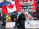 Eine Person schwenkt am 14. Februar 2022 in Ottawa eine kanadische Flagge vor Transparenten zur Unterstützung von Truckern. 