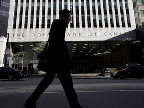 A pedestrian passes in front of a Royal Bank of Canada building in Toronto.
