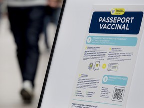 People walk by a sign at a restaurant advising customers of Quebec’s COVID-19 vaccine passport in Montreal.