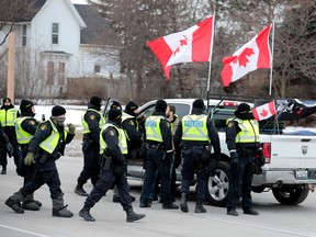 Police surround a pickup truck as they clear protestors against COVID-19 vaccine mandates who blocked the entrance to the Ambassador Bridge in Windsor, Ont., on Feb. 13, 2022.