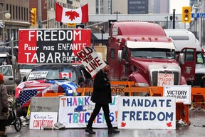 A protester walks in front of parked trucks as demonstrators continue to protest the vaccine mandates in Ottawa Tuesday.